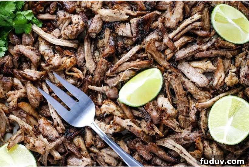 Taco Party Menu Ideas for a Crowd: Recipes, Sides & Drinks 3 Closeup of pork carnitas meat with a fork and garnished with lime wedges.