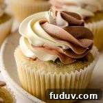 A cupcake with vanilla/chocolate swirled frosting piped on top.