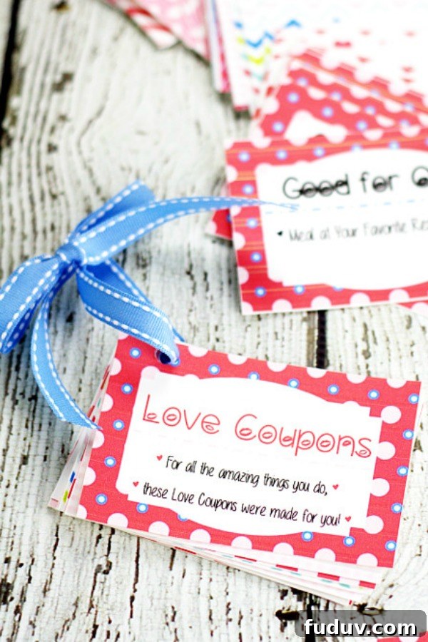 Free Printable Love Coupon book tied together with blue ribbon sitting on a white wood background