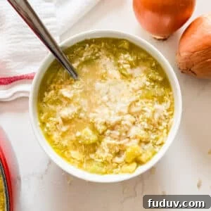 An overhead image of a bowl of zucchini soup with onions and a tea towel next to it.