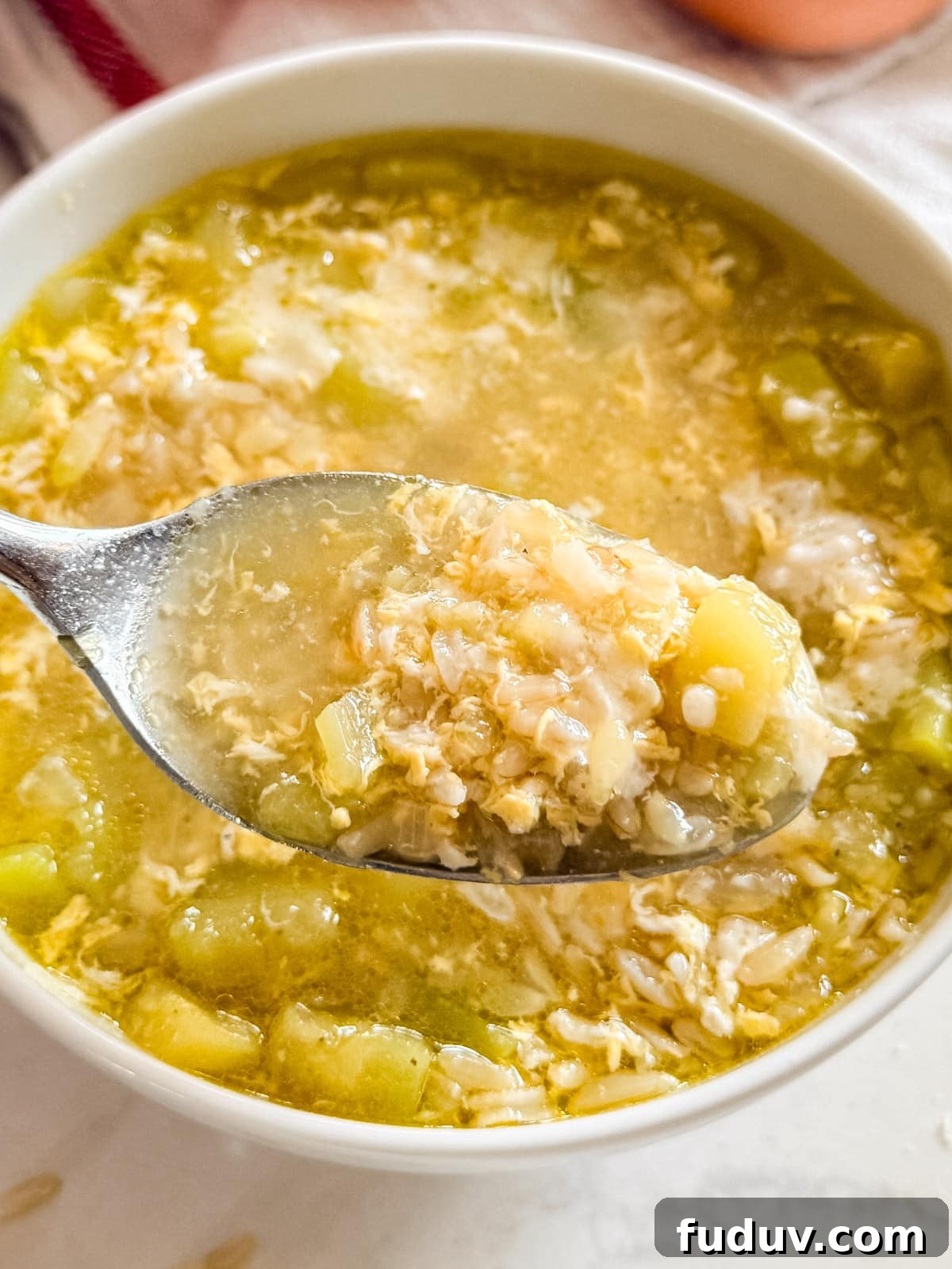 A close up of a spoon full of zucchini soup being pulled from the bowl.
