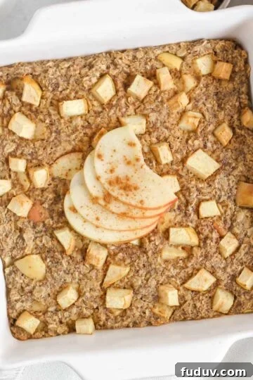 Baked apple oatmeal topped with apple slices in a square white baking dish