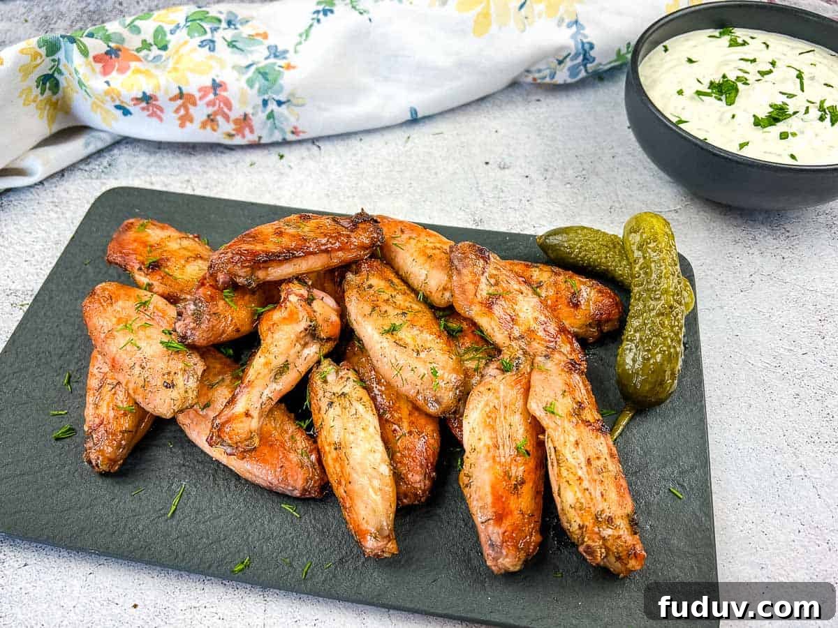 Smoked chicken wings with pickles on a black plate.