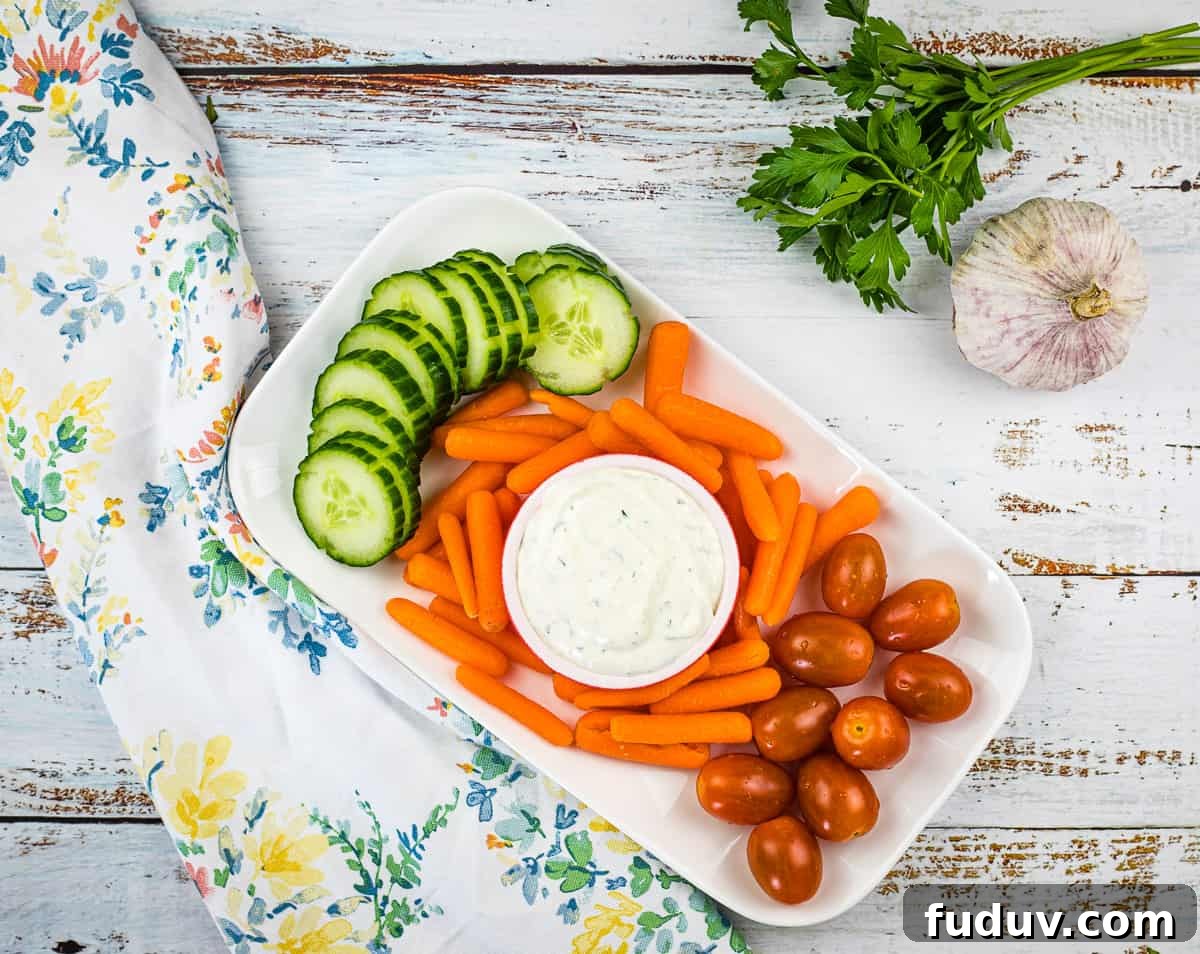 A plate with carrots, cucumbers and garlic dip.