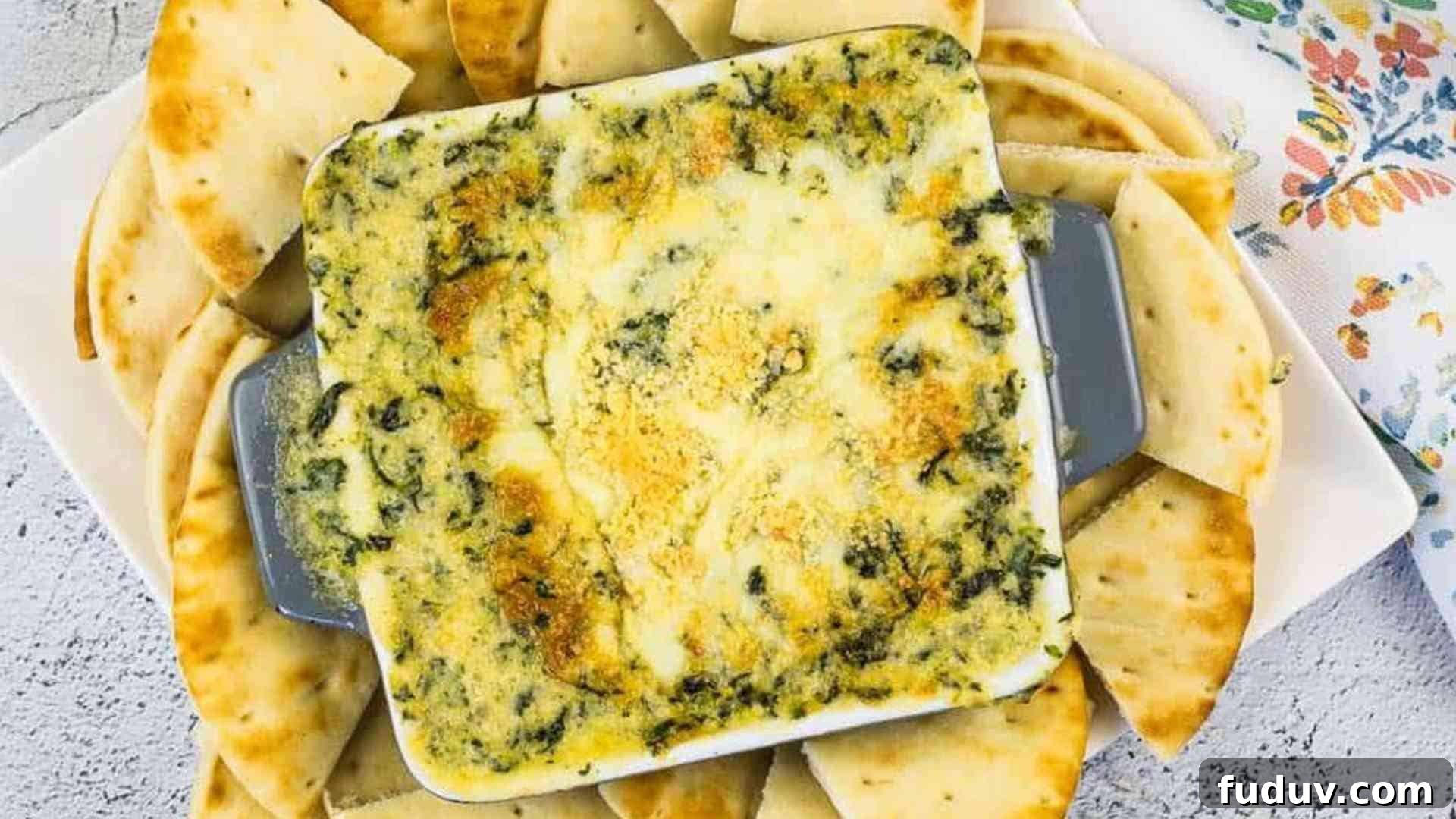 Spinach & Brie Dip in a casserole dish surrounded by pita wedges.