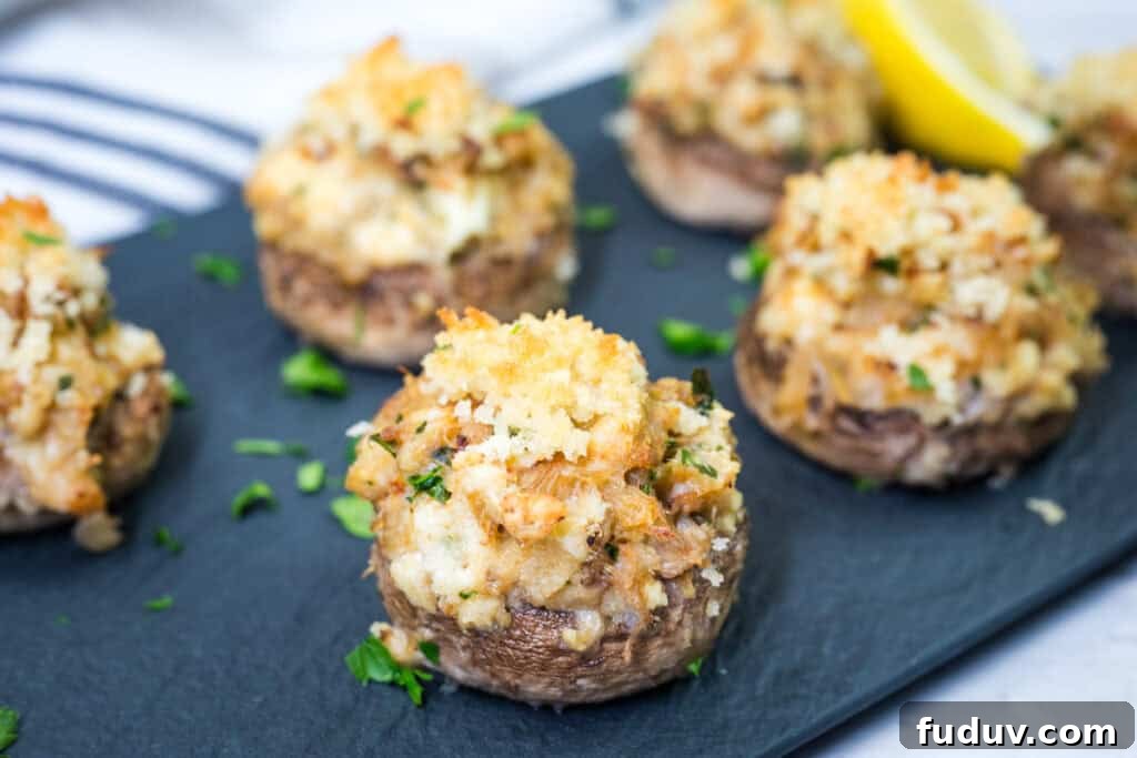 Close-up of Crab Stuffed Mushrooms garnished with chopped parsley on a slate plate.