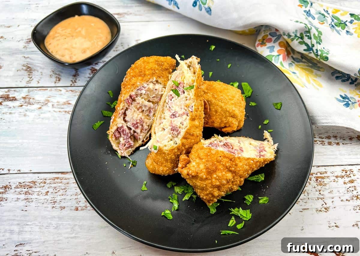 A black plate with Reuben Egg Rolls and dipping sauce.