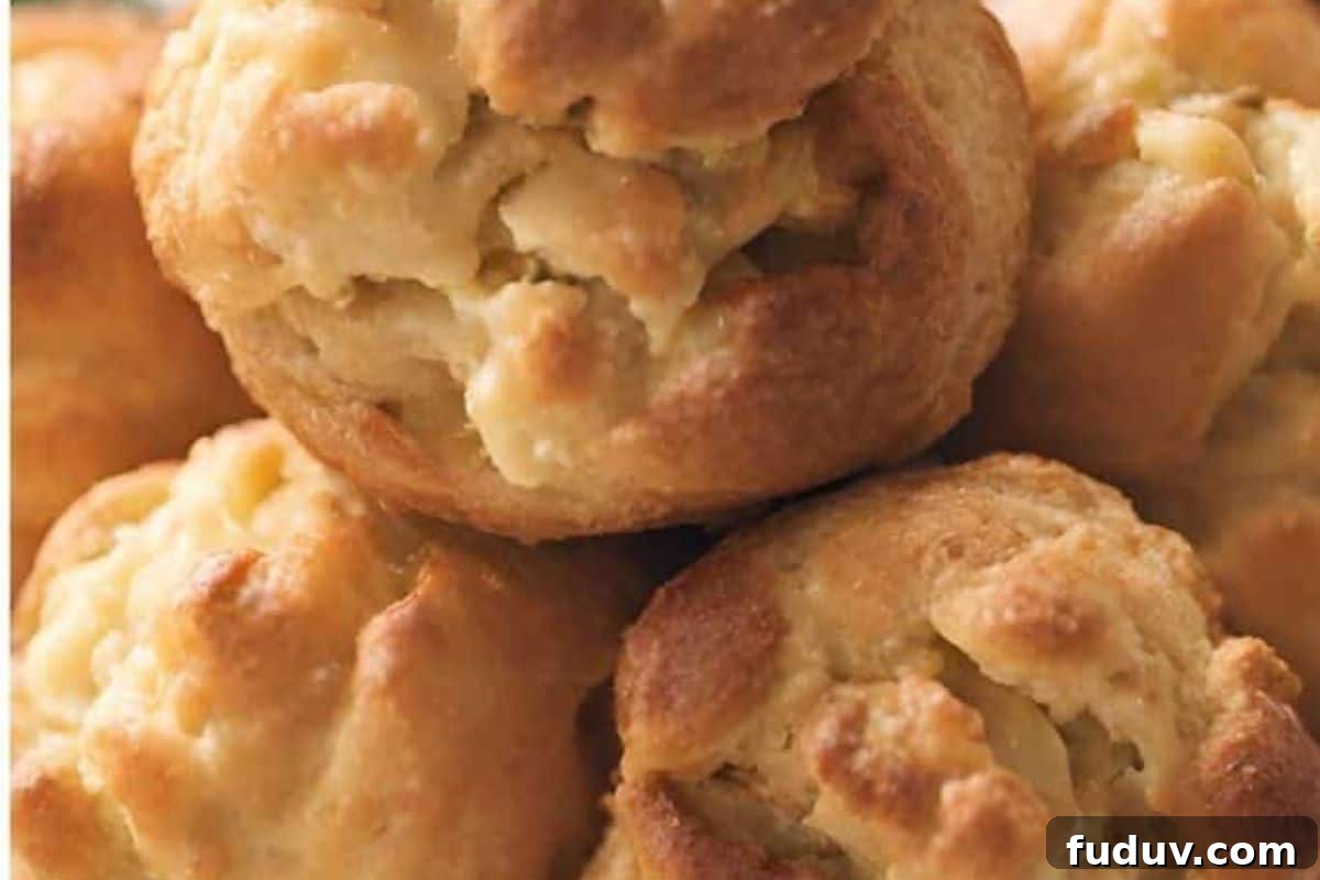 A plate of Gougeres served on a wooden table, with a piece of cheese visible to the side.