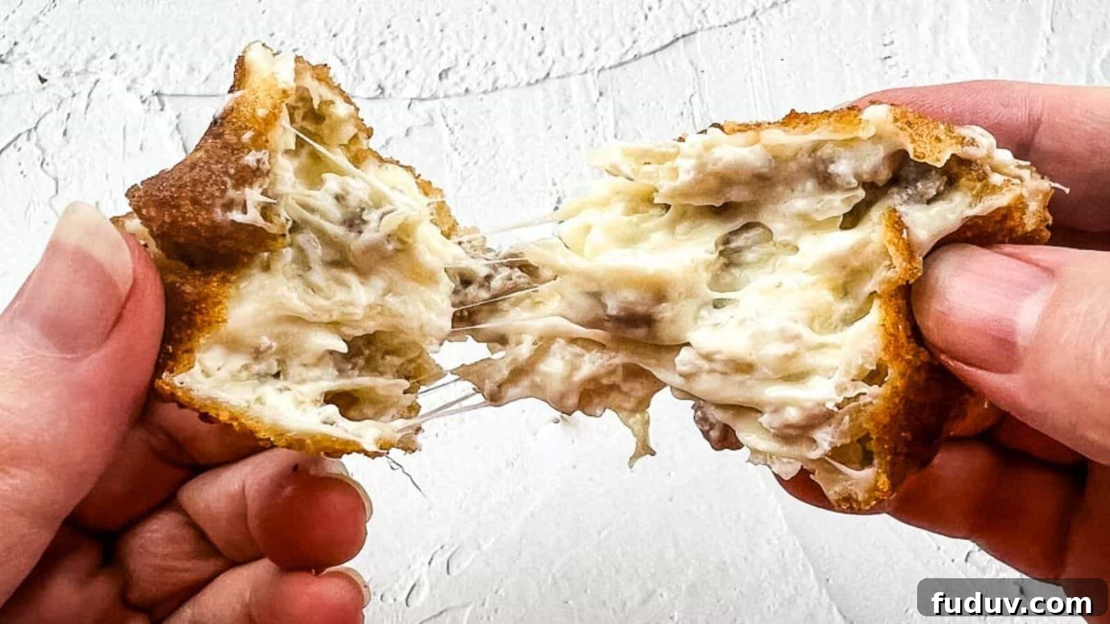 A close-up shot of hands pulling apart a crispy, golden-brown, cheese-filled snack with a gooey, melted cheese center against a textured white background.