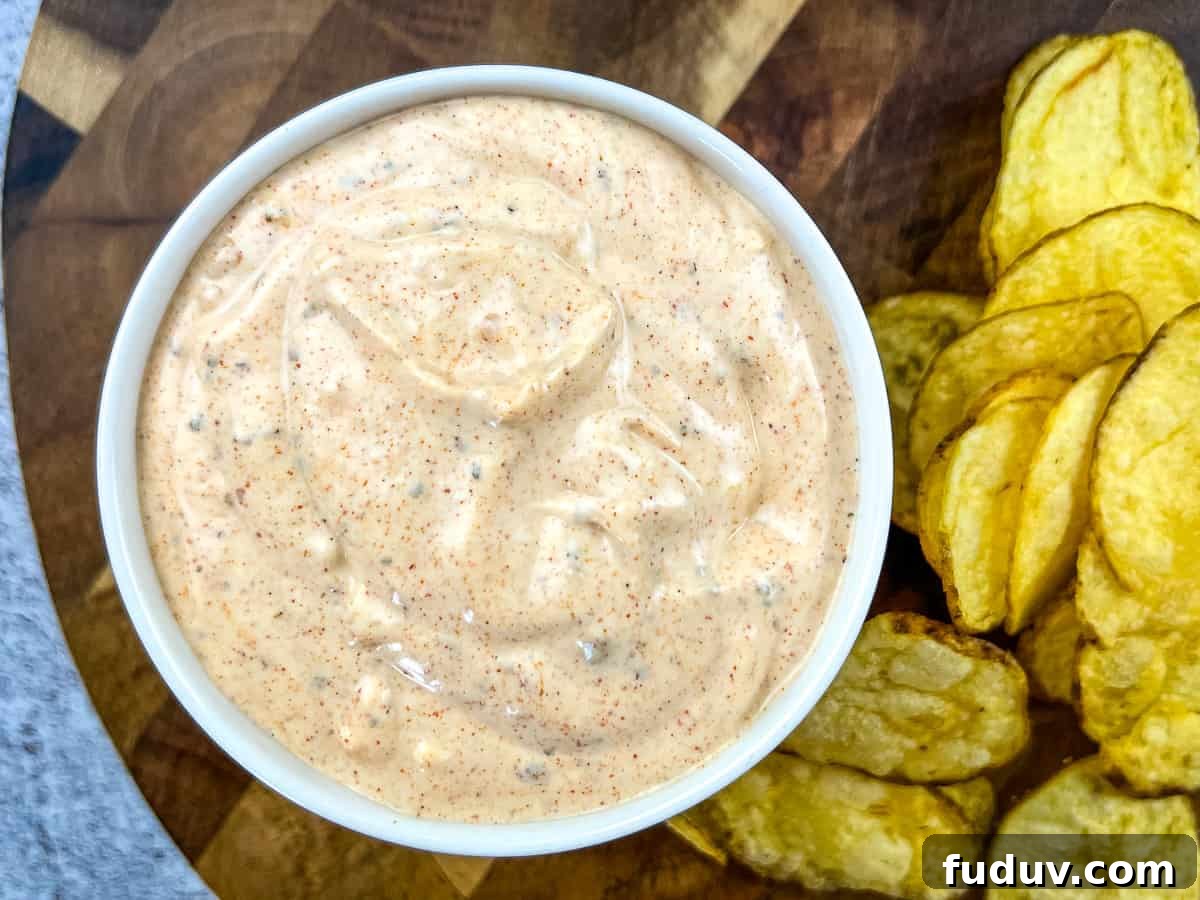 A person dipping a pretzel into a bowl of cajun dip.