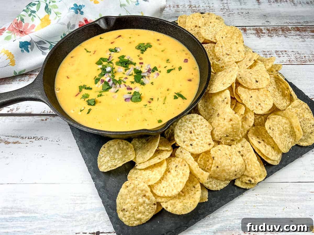 Velveeta queso in a skillet with tortilla chips and lime wedges.
