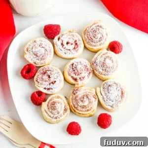 Nine Raspberry Pinwheels on white plate with fresh raspberries.