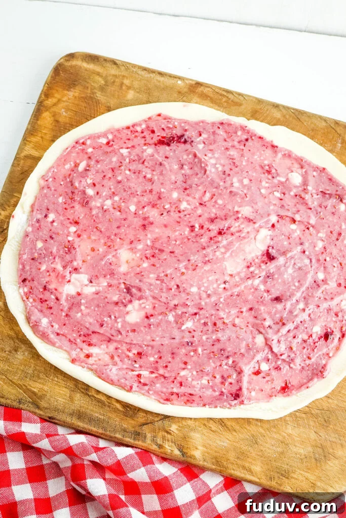 Raspberry cream cheese filling spread on pie dough ready to roll.