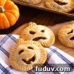 Several apple hand pies in the shape of pumpkins, with carved faces for Halloween.