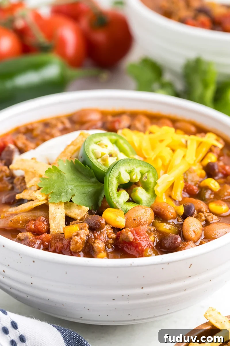 Taco soup with ground beef in a white bowl.