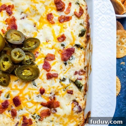 Overhead shot of jalapeno popper dip in white baking dish with crackers on side.