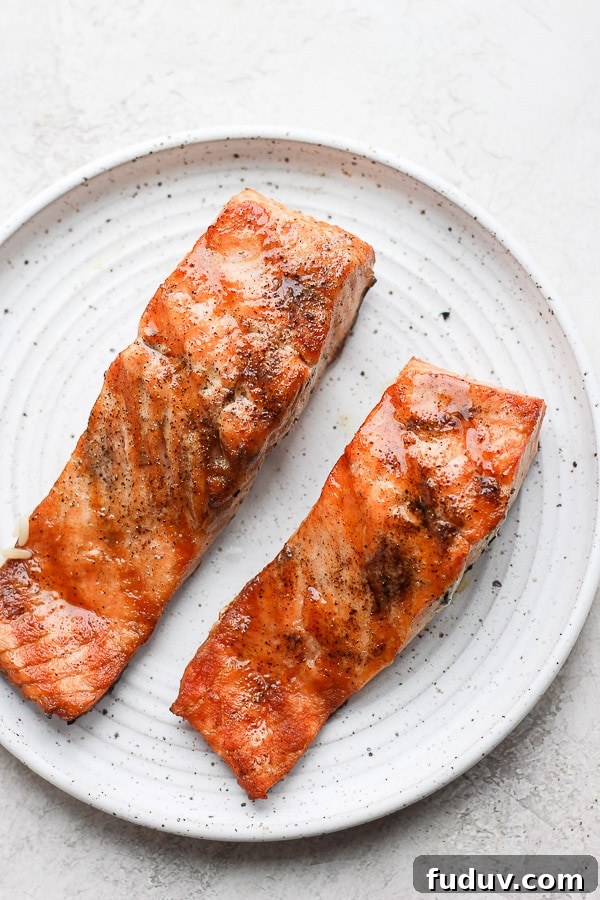 Two pieces of grilled salmon on a plate. 