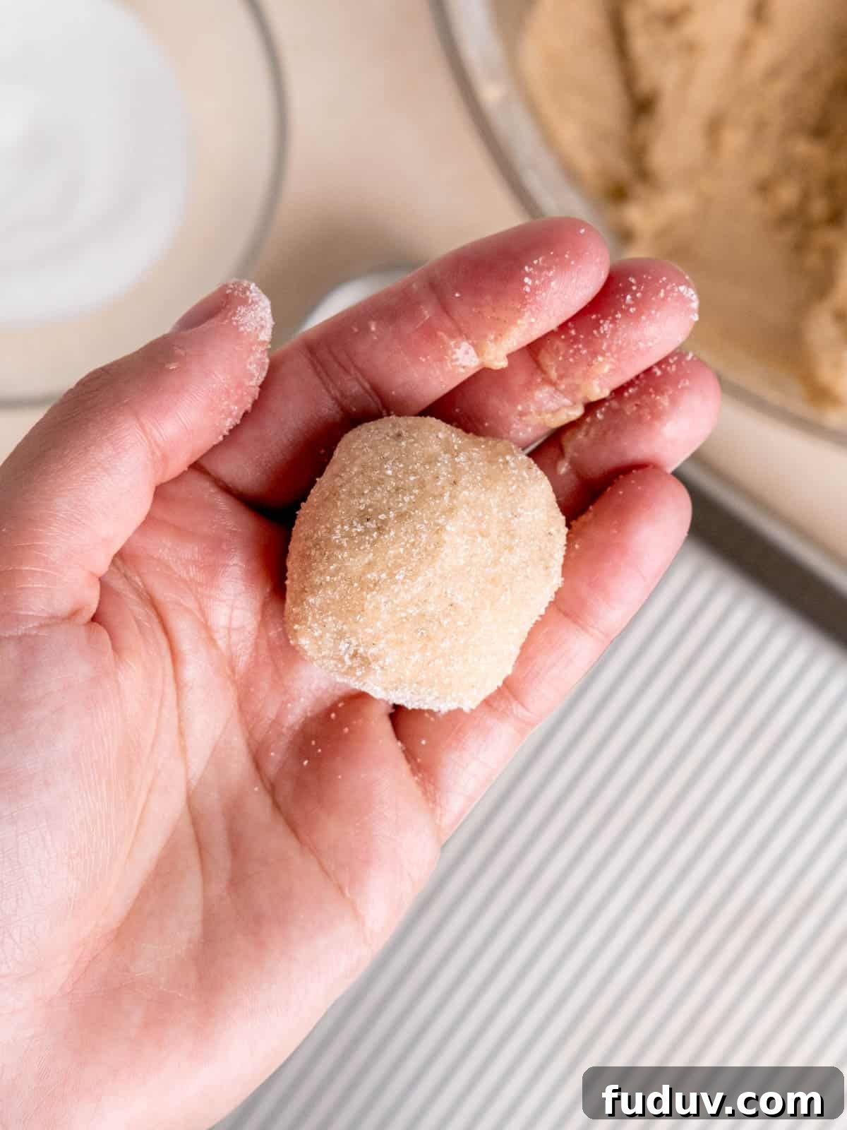 A hand holding a chai cookie covered in sugar.