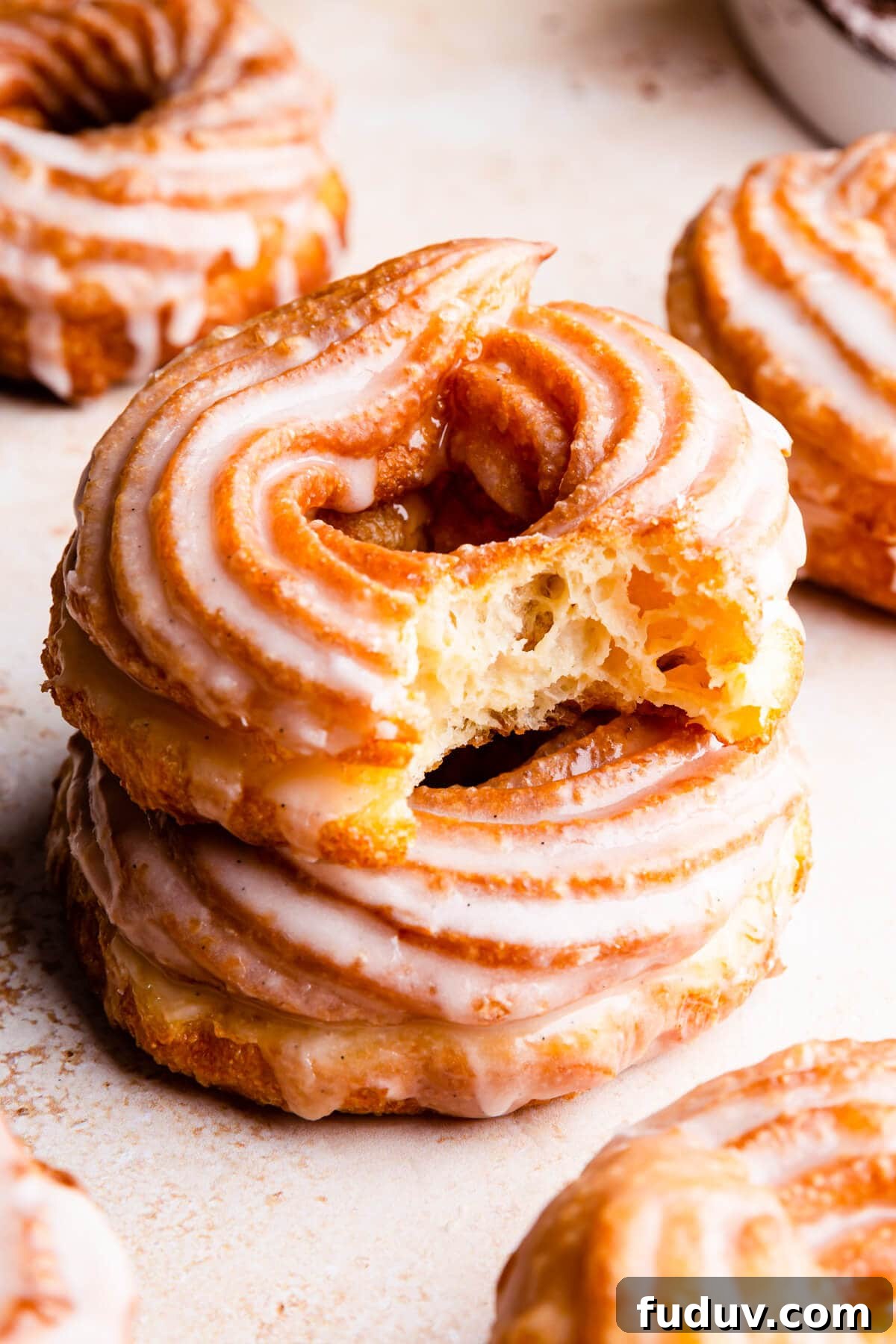 How to Make Classic French Crullers at Home 2 side super close up at glazed cruller doughnut with bite missing on top of another doughnut