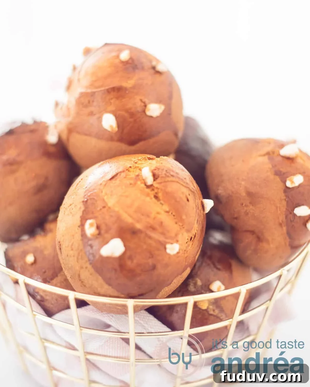 Dutch Suikerbrood: Traditional Cinnamon Sugar Buns Recipe 2 A basket filled with sugar rolls, lying on a pink white tea towel on a white background