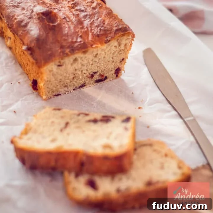 A square picture with a cranberry loaf on a baking paper. Two slices cut off.