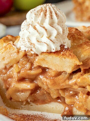 Baked caramel apple pie slice with whipped cream on top.