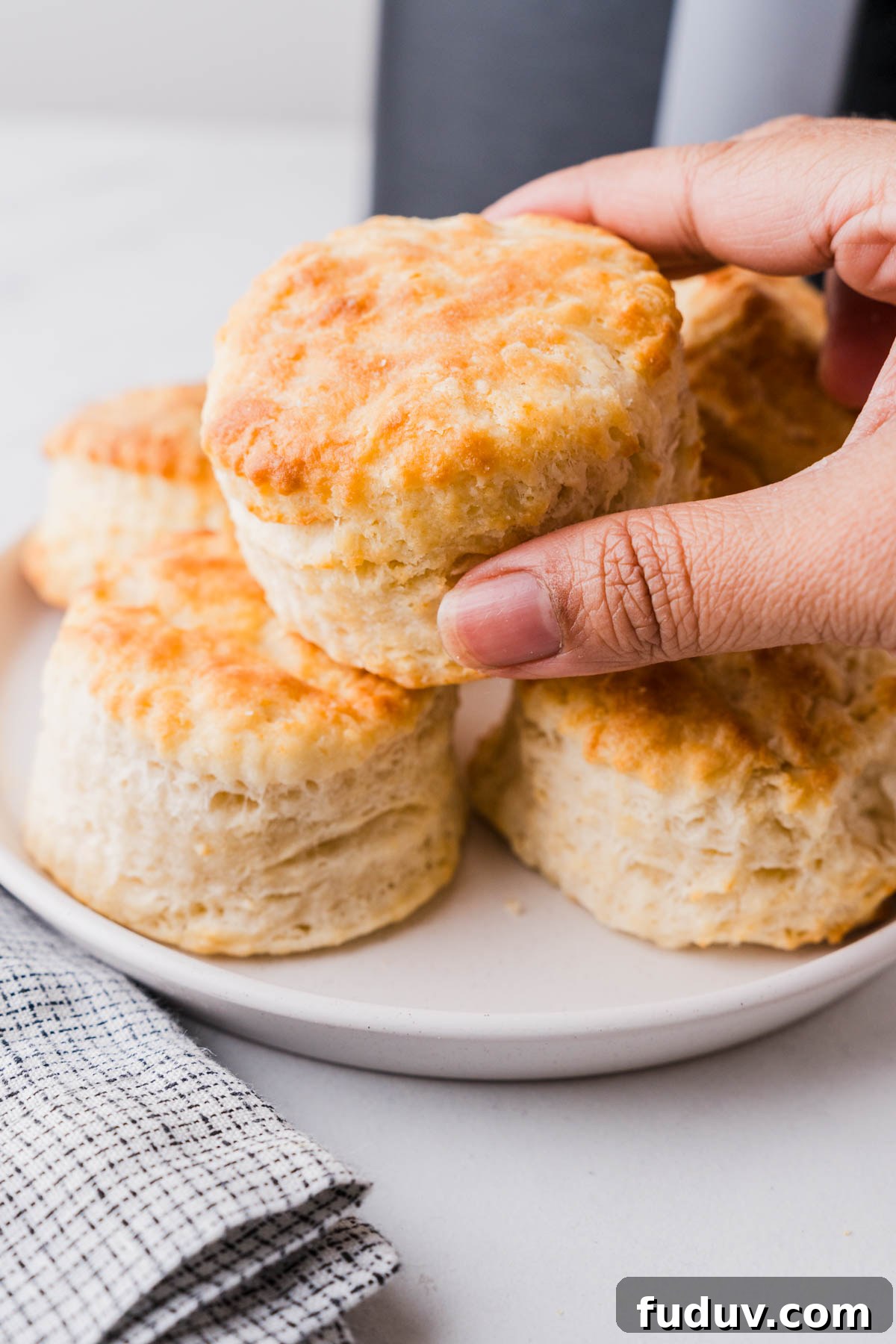 Crispy Air Fryer Biscuits: Quick Flaky Homemade Recipe 14 picking an air fryer biscuit from the plate.