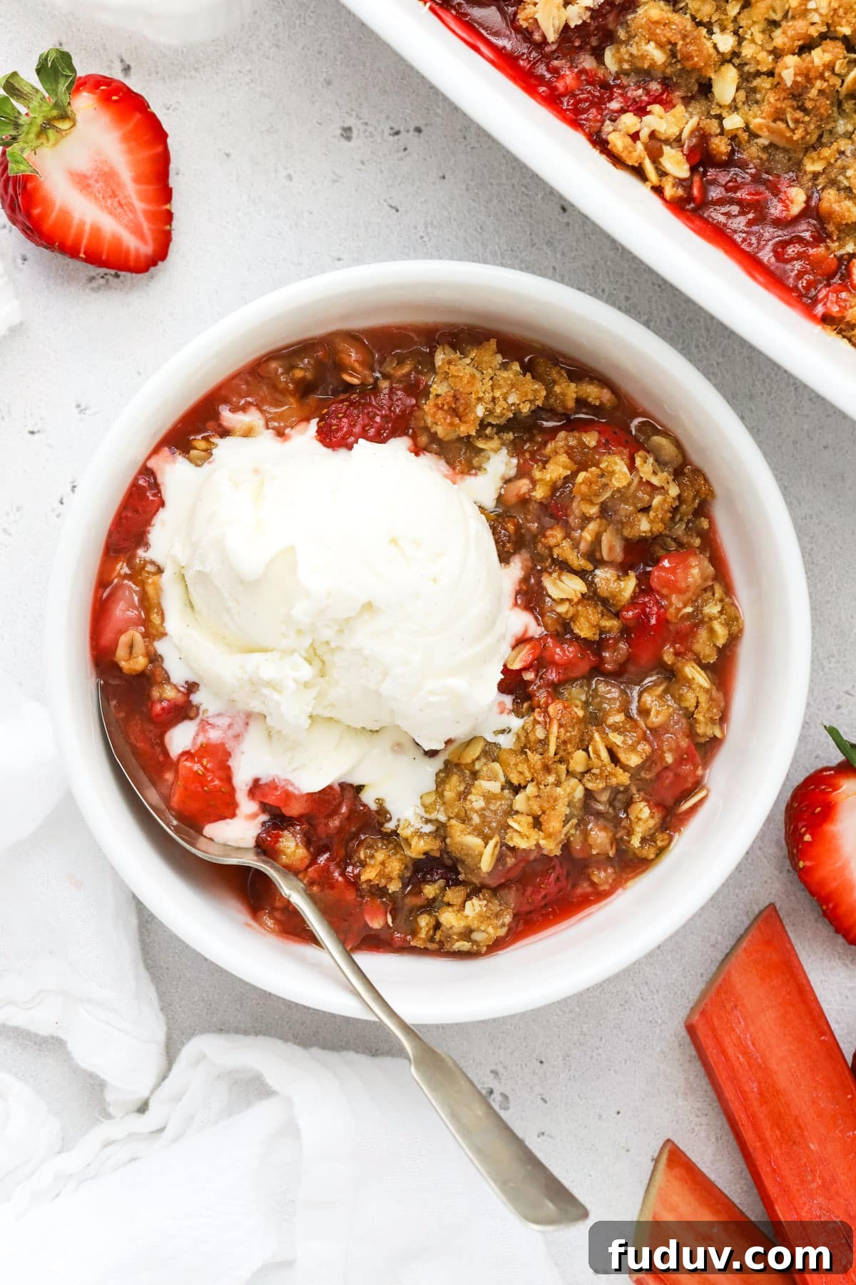 a bowl of gluten-free strawberry rhubarb crisp topped with a scoop of vanilla ice cream