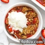 a bowl of gluten-free strawberry rhubarb crisp topped with a scoop of vanilla ice cream