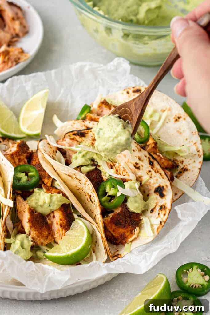 Grilled Salmon Tacos with Creamy Avocado Lime Crema 8 Spooning the avocado crema over the assembled tacos.