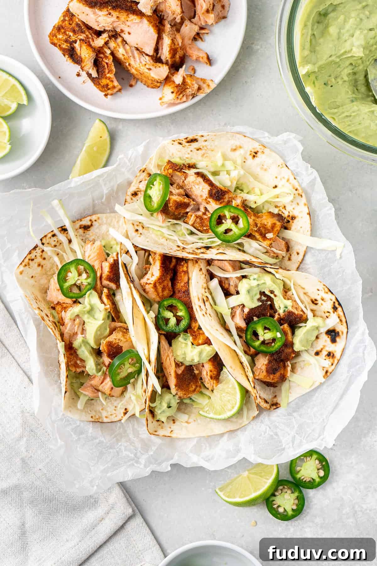 Grilled Salmon Tacos with Creamy Avocado Lime Crema 9 Grilled salmon tacos on a plate with fresh jalapeños as garnish.