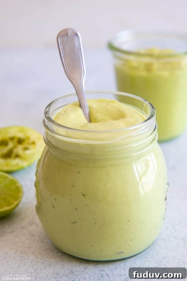 avocado ranch a spoon being dipped in a small jar with with vegan healthy avocado ranch dip