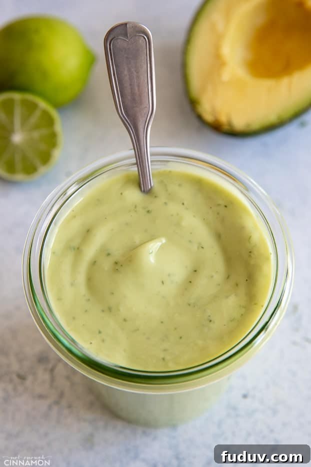 avocado ranch dressing a small spoon in a jar with homemade vegan Avocado Ranch dressing