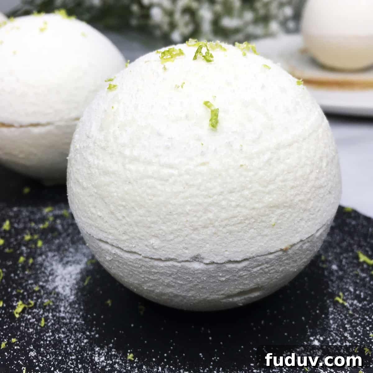 Meringue spheres served on a black slate board with a dessert plate and flowers aside.