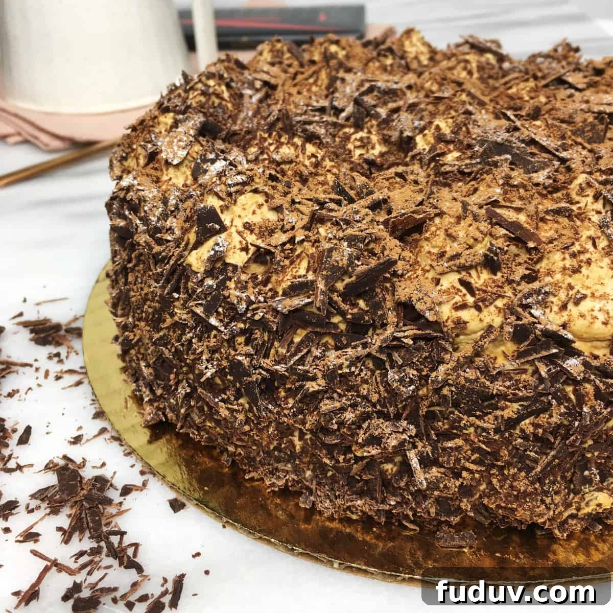 French Meringue Cake Merveilleux on a cake round with chocolate shavings and a cup on background.