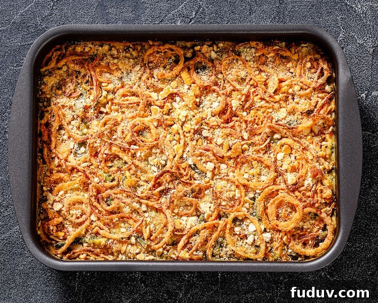 Green bean casserole in a large dish topped with crispy French fried onions and parmesan cheese.
