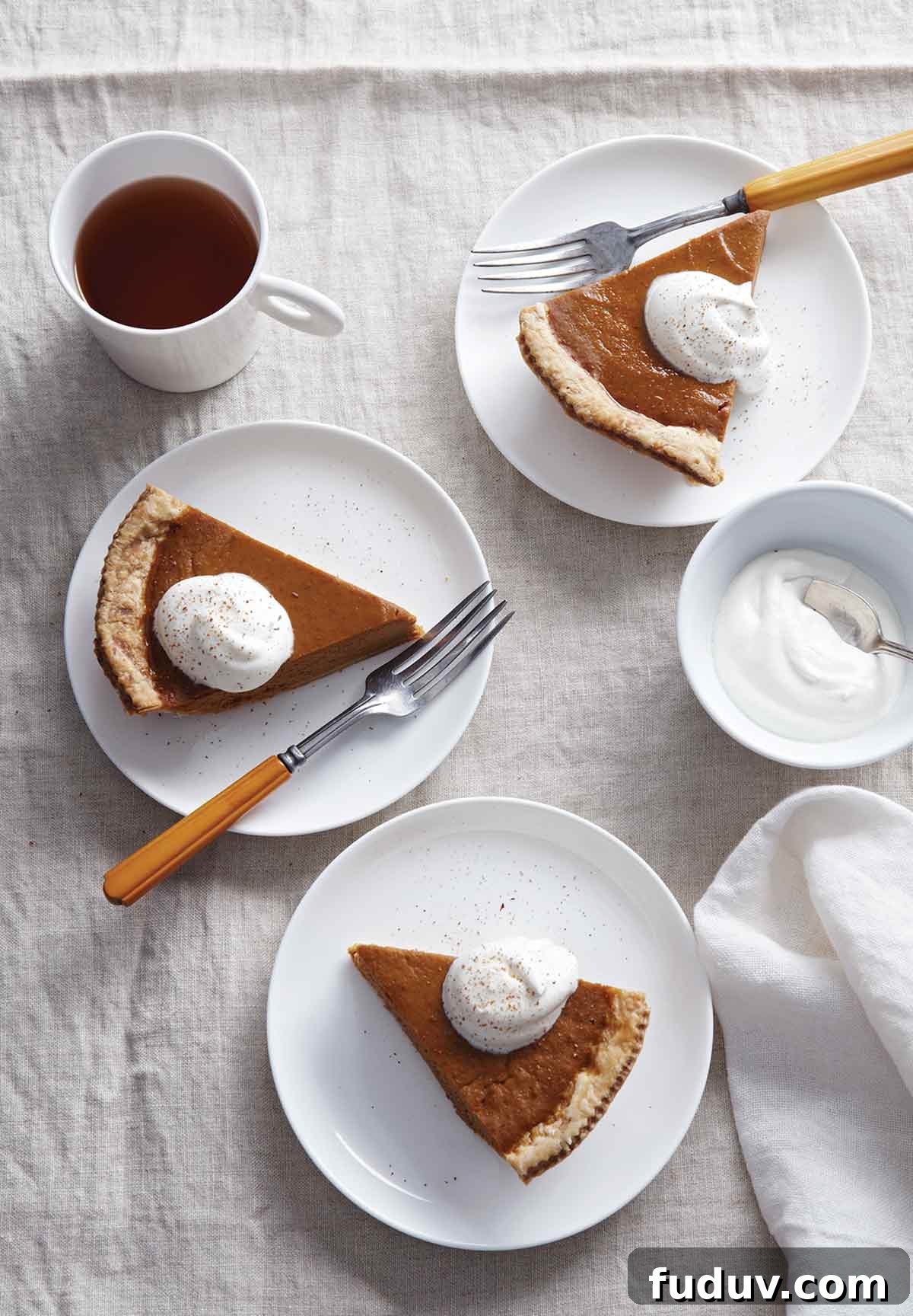 Maple pumpkin pie slices on 3 plates, topped with whipping cream.