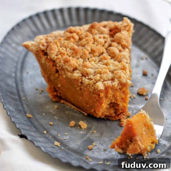 A wedge of bourbon sweet potato pie topped with a crumbly brown sugar streusel on a metal plate.