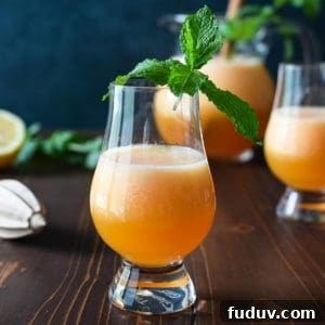 Eye level view of canteloupe lime agua fresca on a wooden background with mint in the glass