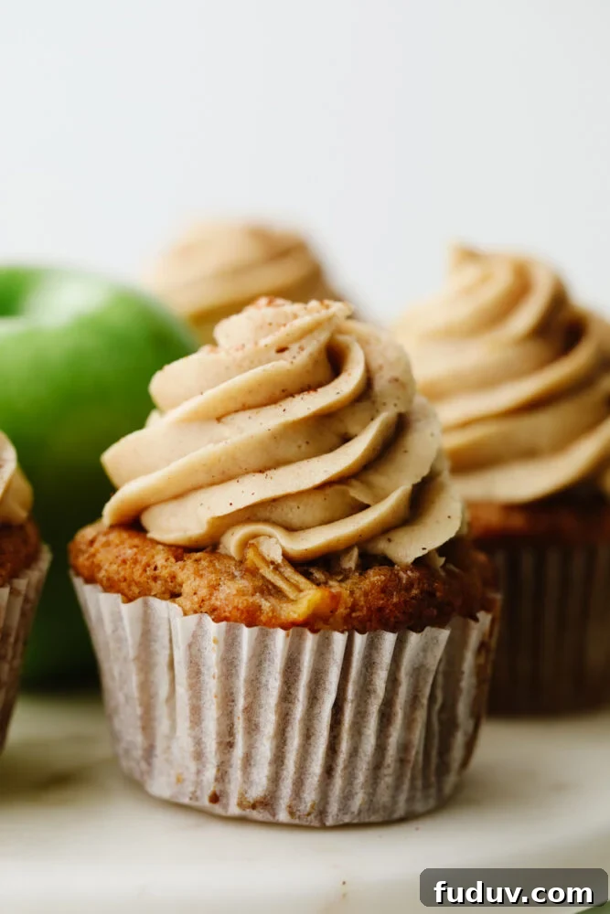 Apple pie cupcakes are a twist on a classic dessert. They are moist, delicious and with fresh apple pie filling in the middle, they give you JUST the right amount of texture! Close up of an apple pie cupcake.