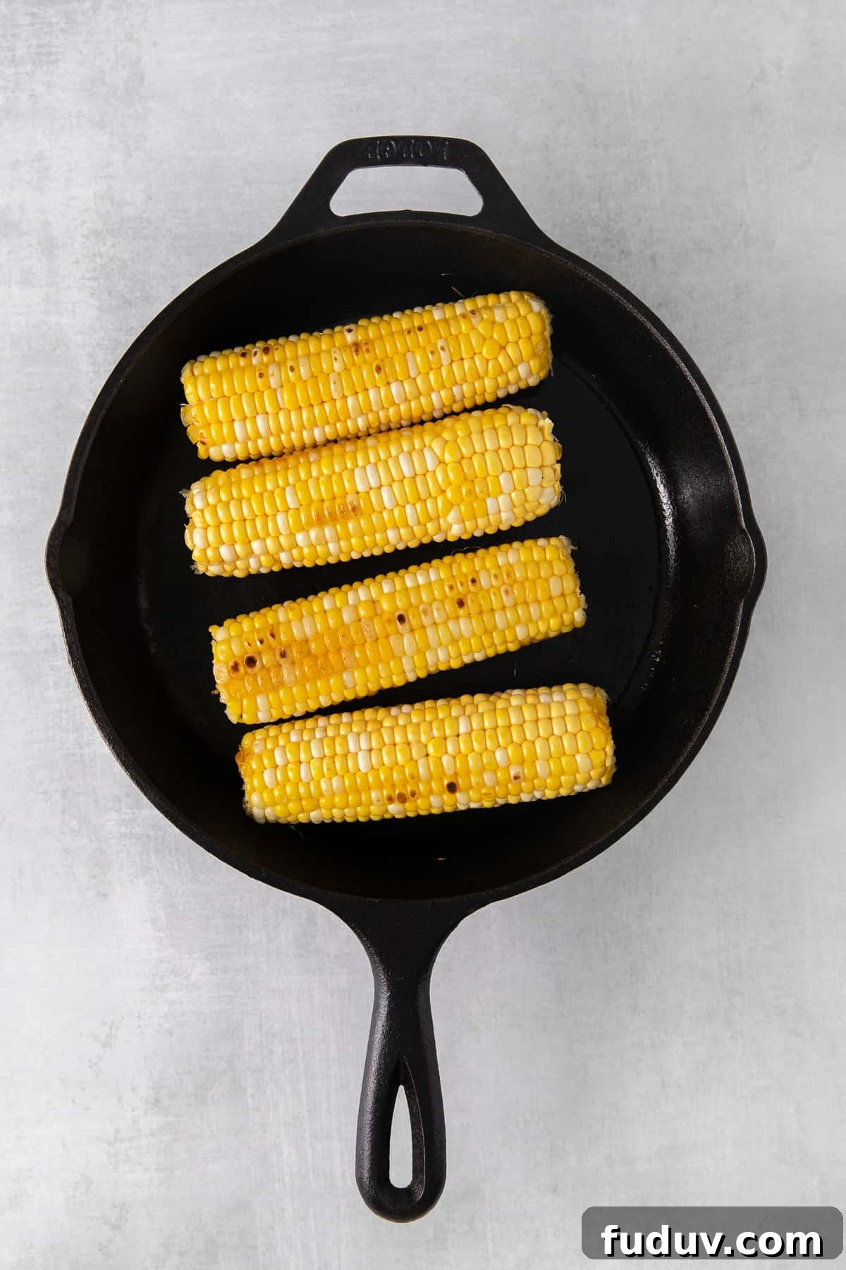 Corn on the cob browning in a cast iron skillet.