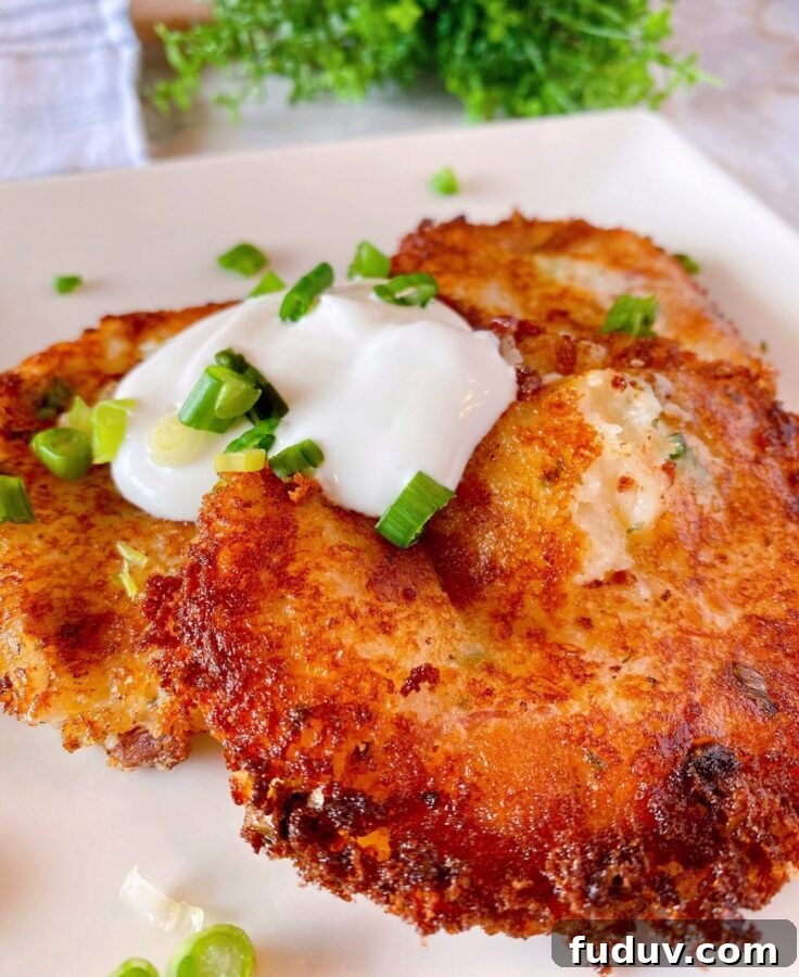 Loaded Mashed Potato Cakes on a plate with sour cream and chives