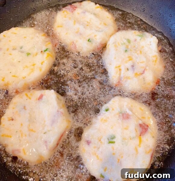 Skillet filled with hot oil and frying mashed potato patties.
