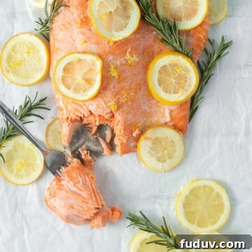 baked lemon butter salmon with lemon rounds on parchment paper.