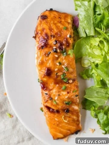 sesame ginger salmon on a white plate with a simple green salad.