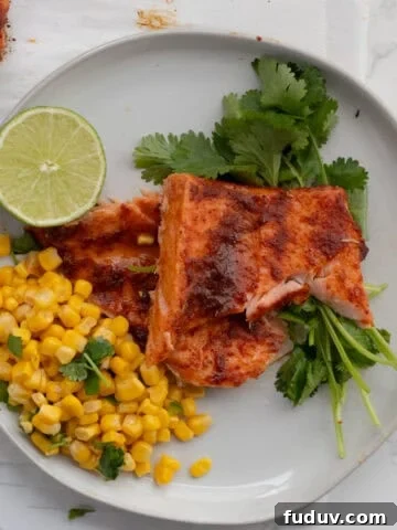 chili lime salmon on a white plate with corn and a lime