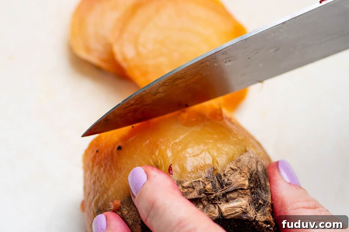Slicing a golden beet with large knife on cutting board.