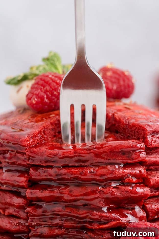 Red Velvet Pancakes Recipe with Video Tutorial 4 a fork going into a big stack of red pancakes