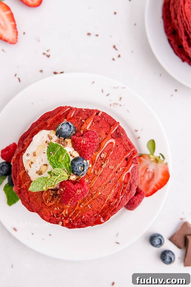 Red Velvet Pancakes Recipe with Video Tutorial 6 a stack of red velvet pancakes with fruit on and around the stack