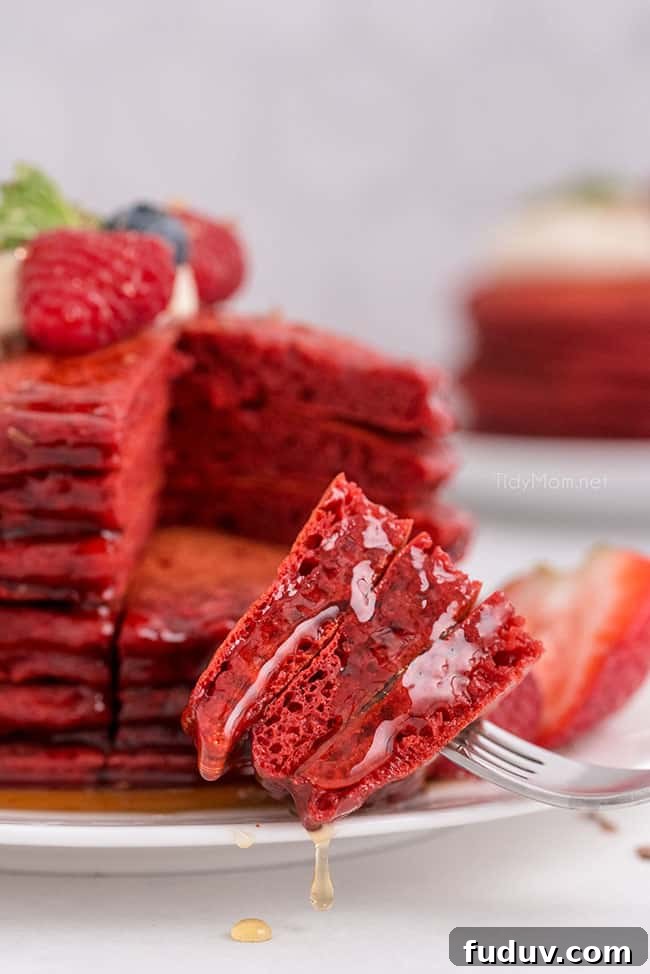 Red Velvet Pancakes Recipe with Video Tutorial 7 a bite of pancakes on a fork with syrup dripping off